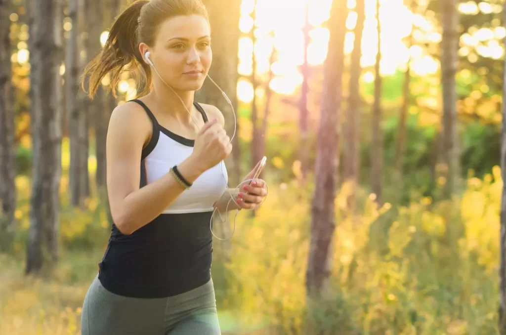 Mujer corriendo al aire libre como ejercicio físico para mejorar el bienestar