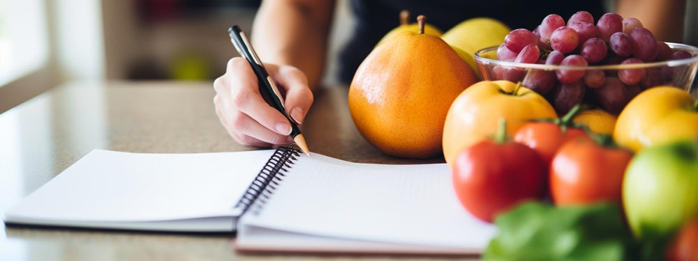 Persona planificando una alimentación saludable con frutas frescas representando hábitos saludables