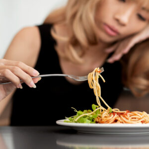 Mujer con síntomas de depresión frente a un plato de comida, representando la relación entre dieta cetogénica, metabolismo y salud mental