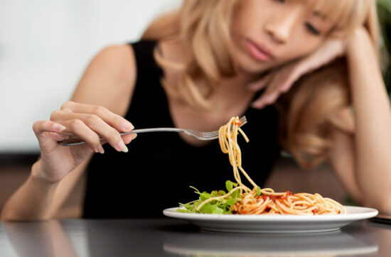 Mujer con síntomas de depresión frente a un plato de comida, representando la relación entre dieta cetogénica, metabolismo y salud mental