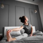 Mujer estirándose sobre la cama para activar el cuerpo y recuperar energía frente al cansancio y la desmotivación.