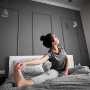 Mujer estirándose sobre la cama para activar el cuerpo y recuperar energía frente al cansancio y la desmotivación.