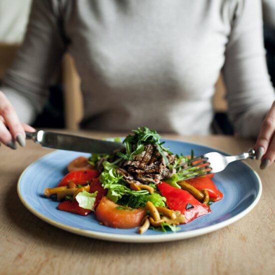 Mujer comiendo ensalada saludable, ejemplo de exceso de alimentos crudos que puede provocar hinchazón y gases