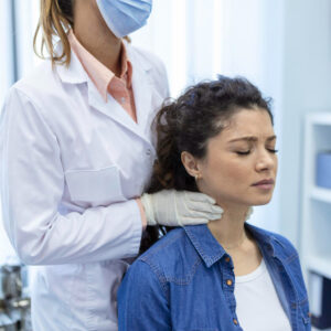 Exploración médica de la tiroides en una mujer, relacionada con el impacto del estrés emocional en la salud hormonal