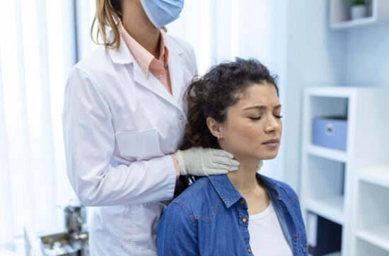 Exploración médica de la tiroides en una mujer, relacionada con el impacto del estrés emocional en la salud hormonal