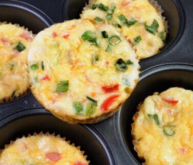Muffins salados de verduras y huevo con pimiento, cebolla y hierbas frescas en molde para muffins