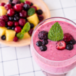 Smoothie de piña y frutos rojos con jengibre fresco, decorado con menta, bebida antioxidante natural y digestiva