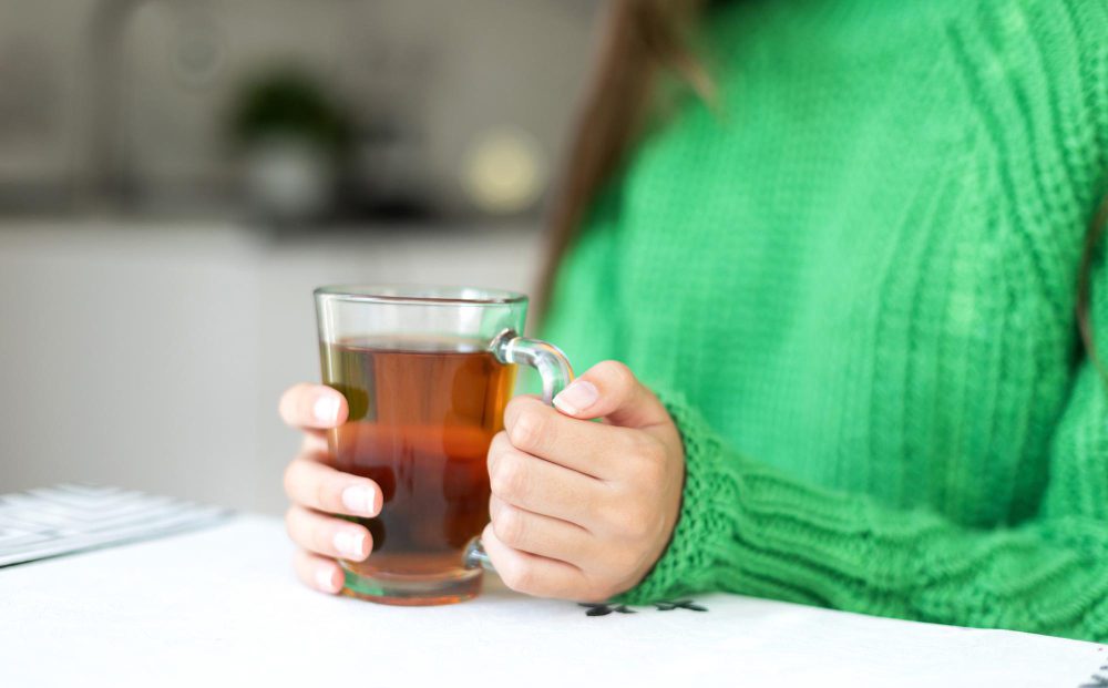 Mujer bebiendo té verde en casa, relacionado con las contraindicaciones del té verde y sus efectos en la salud