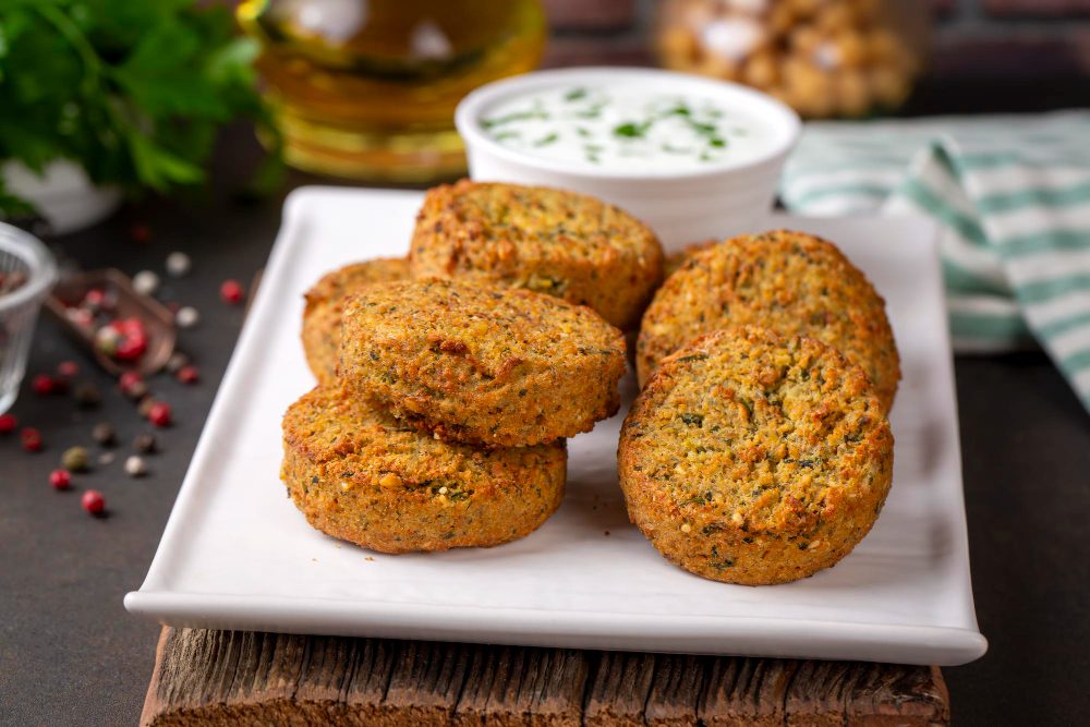 Falafel de lentejas rojas crujientes servidos en plato blanco con salsa de tahini