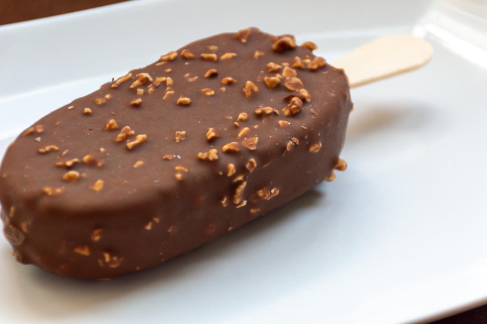 Helado proteico casero con chocolate negro y almendras sobre plato blanco