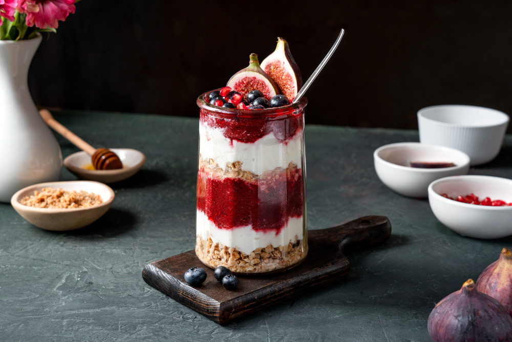 Yogur de coco con compota de higos y granola en capas decorado con arándanos y granada